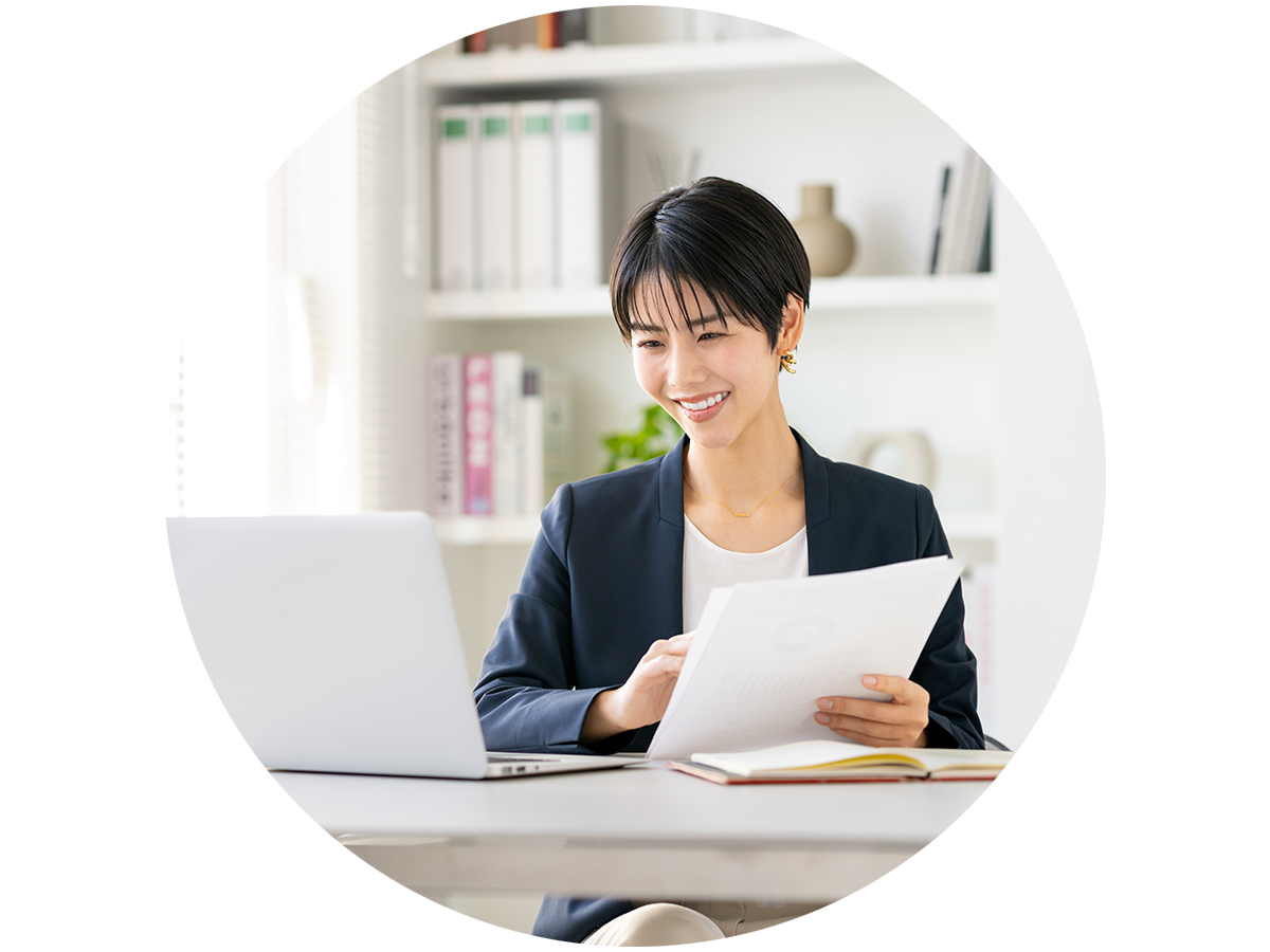 Person sitting in front of a laptop holding a document