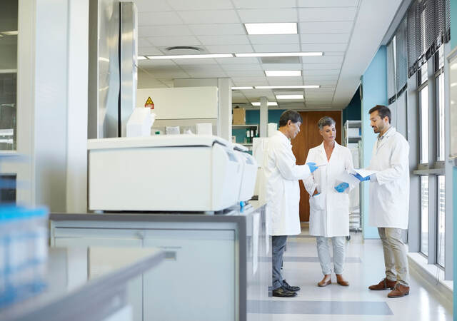 Group of lab technicians standing together looking at documents