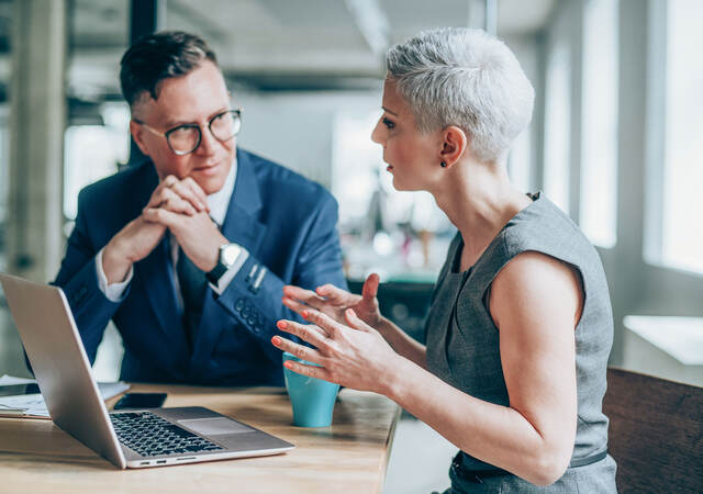 Two people having a discussion in front of a laptop 