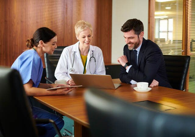 Business person sitting at a conference table with two medical professionals