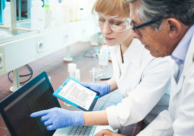 Two lab technicians looking at data on a computer