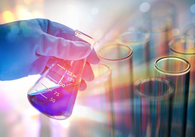 Person looking at blue liquid in an Erlenmeyer flask