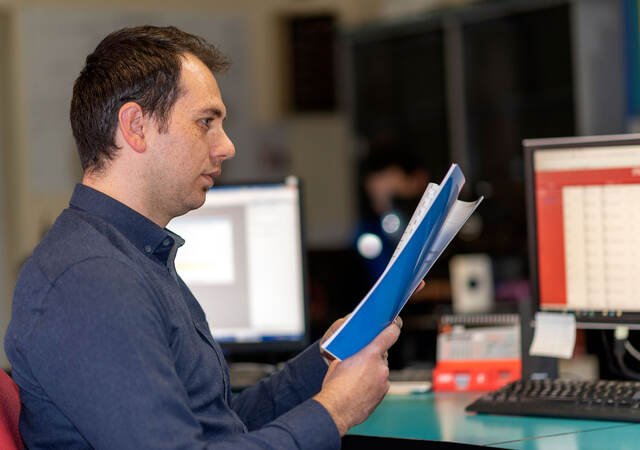 Person standing at a desk looking at documents