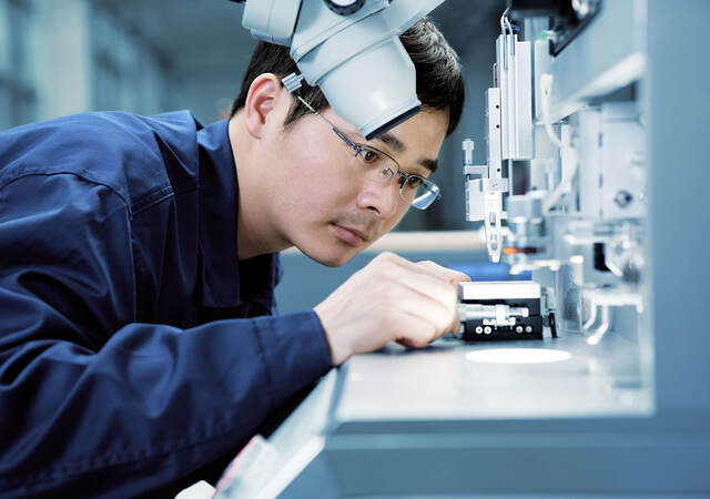 Lab technician placing something under a microscope