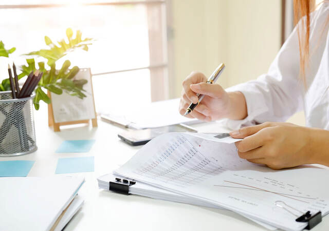 Person sitting at desk reviewing documents with a pen