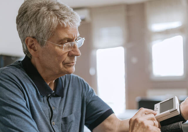 Senior using blood pressure machine in their home