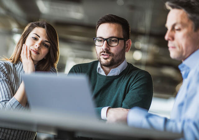 Three people looking at a laptop at work