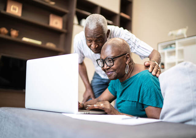 Two senior individuals looking at a laptop