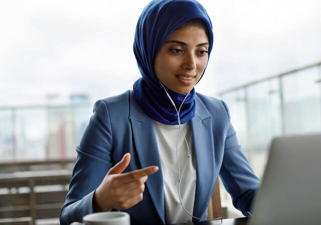 Person wearing headphones and looking at a laptop