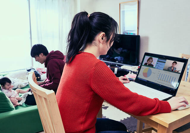 Person working from home as their husband takes care of their child in the background