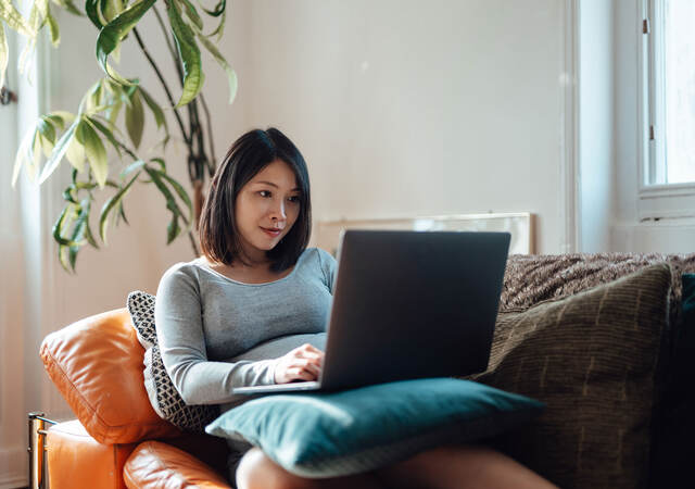 A person sitting on couch using their laptop