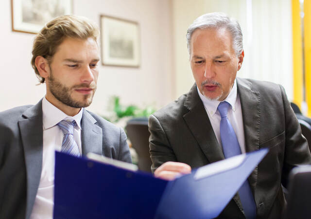 Two men in suits looking over a document