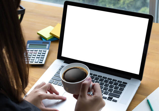 Person with coffee looking at a laptop