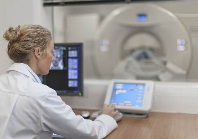 Medical professional using electronic controls to test a medical scanning device.