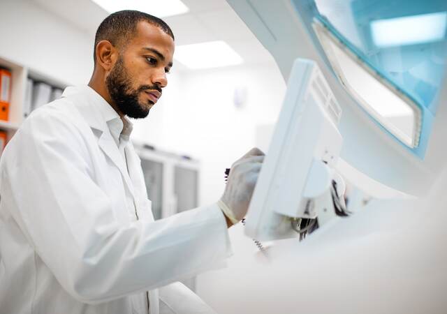 Scientist in lab coat working at the computer screen.