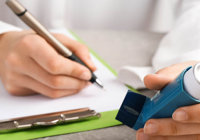 Person taking notes on a clipboard while holding a nebulizer