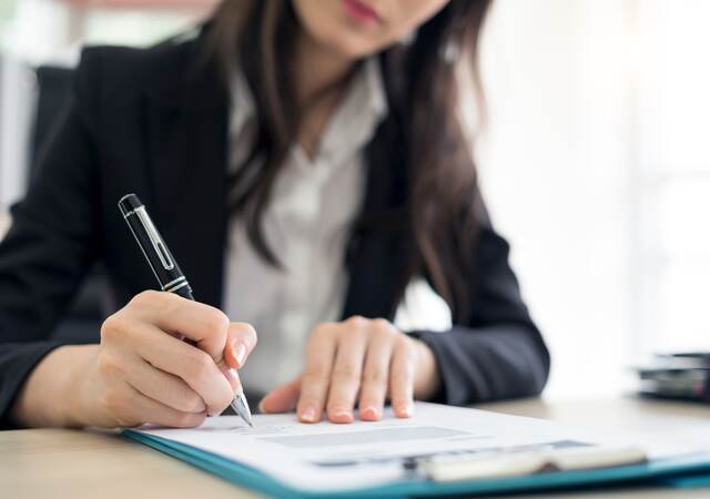 Person signing paperwork in an office 