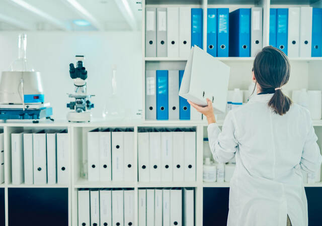 Lab tech putting away a binder on a shelf