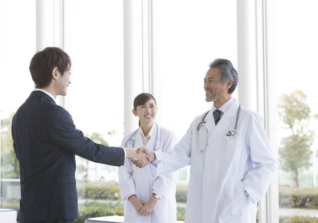 Person in a suit greeting two doctors