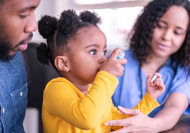 Child using an inhaler with the help of a doctor