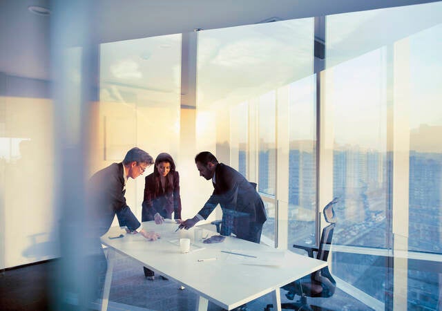 Business colleagues leaning over a table in an office while they work on their business strategy