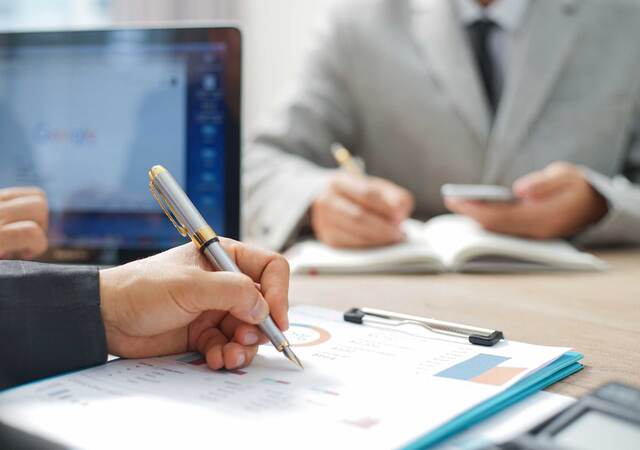 Close up of a person making notes on a printed out report on a clipboard