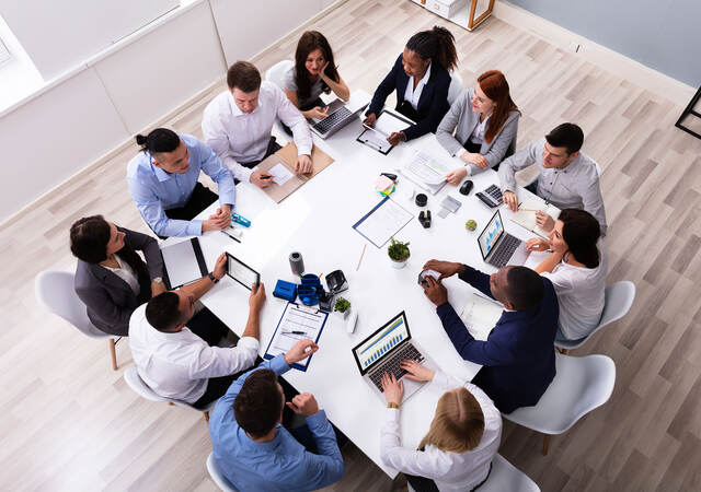 Overhead view of 12 people having a meeting at a square table