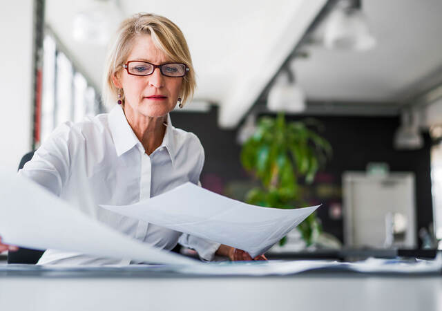 Manager reviewing reports by laying them out on a table