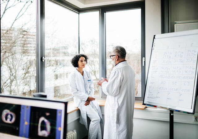 Two doctors talking next to a window in a doctor's office