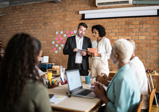 Business colleagues collaborating in front of a brick wall with post-it notes