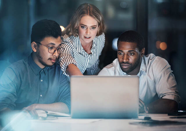 Group of colleagues collaborating in front of a laptop