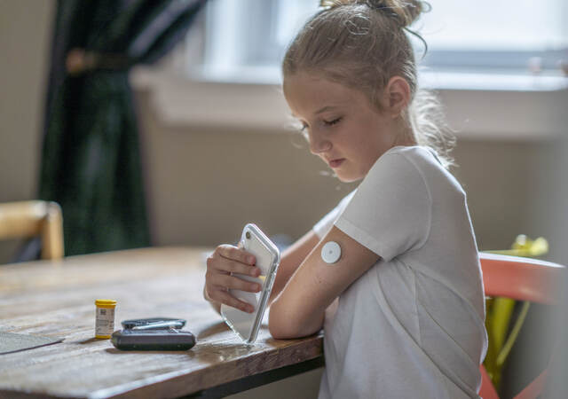 Young person testing their blood sugar with their mobile phone.