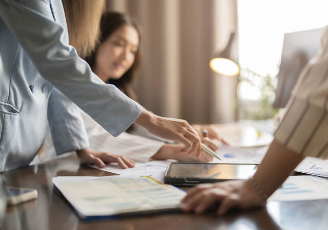 Group of business professionals having a discussion while looking at a tablet on a table