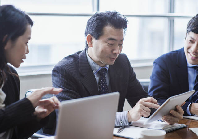 Three coworkers collaborating together in front of a tablet