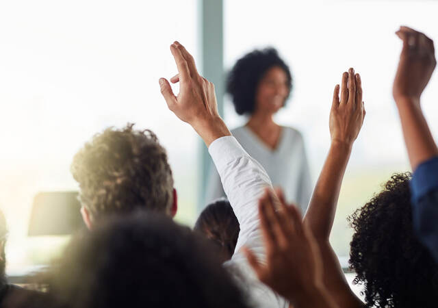 Group of people raising their hands to ask questions