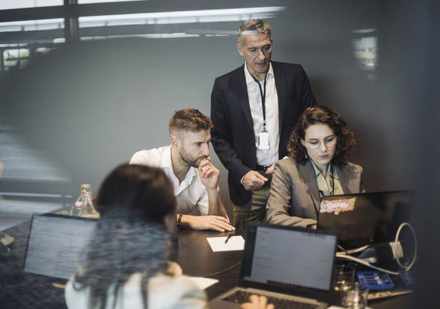 Colleagues collaborating in front of a laptop