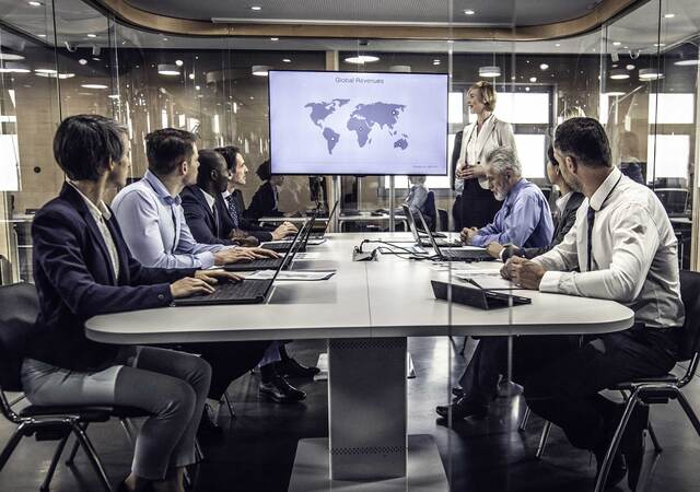 Group of business professionals having a meeting while looking at a map of the world