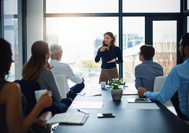 Person standing in front of a conference table to lead a meeting