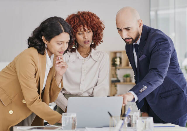 Three business colleagues reviewing content on a laptop