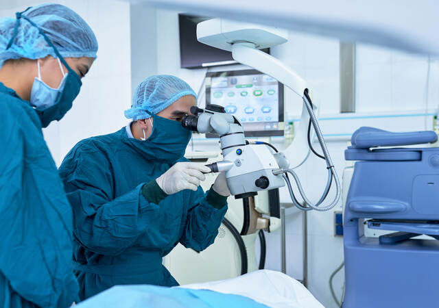 Two ophthalmologists performing operation on a patient's eyes