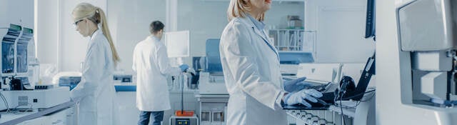 Team of Research Scientists Working On Computer, with Medical Equipment, Analyzing Blood and Genetic Material Samples with Special Machines in the Modern Laboratory.