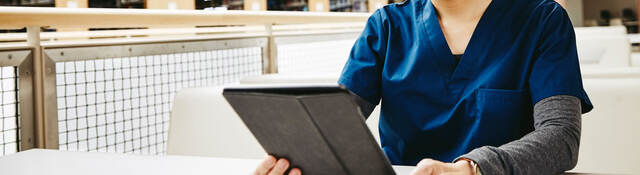 Medical student reading tablet in a library