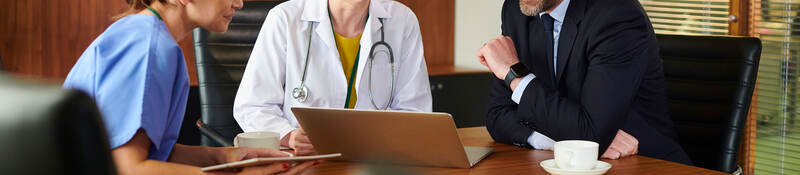 Business person sitting at a conference table with two medical professionals