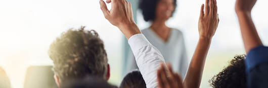 Group of people raising their hands to ask questions