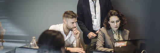 Colleagues collaborating in front of a laptop