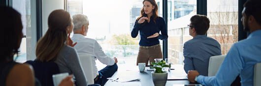 Person standing in front of a conference table to lead a meeting