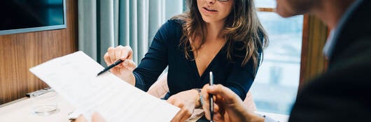 Two business professionals discussing regulations during a meeting