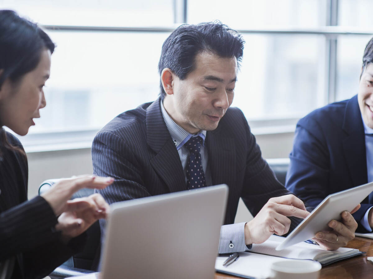 Three coworkers collaborating together in front of a tablet