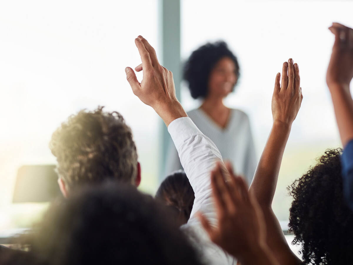 Group of people raising their hands to ask questions